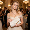 A woman wearing a beige glitter pleated crossbody clutch bag at an elegant event.