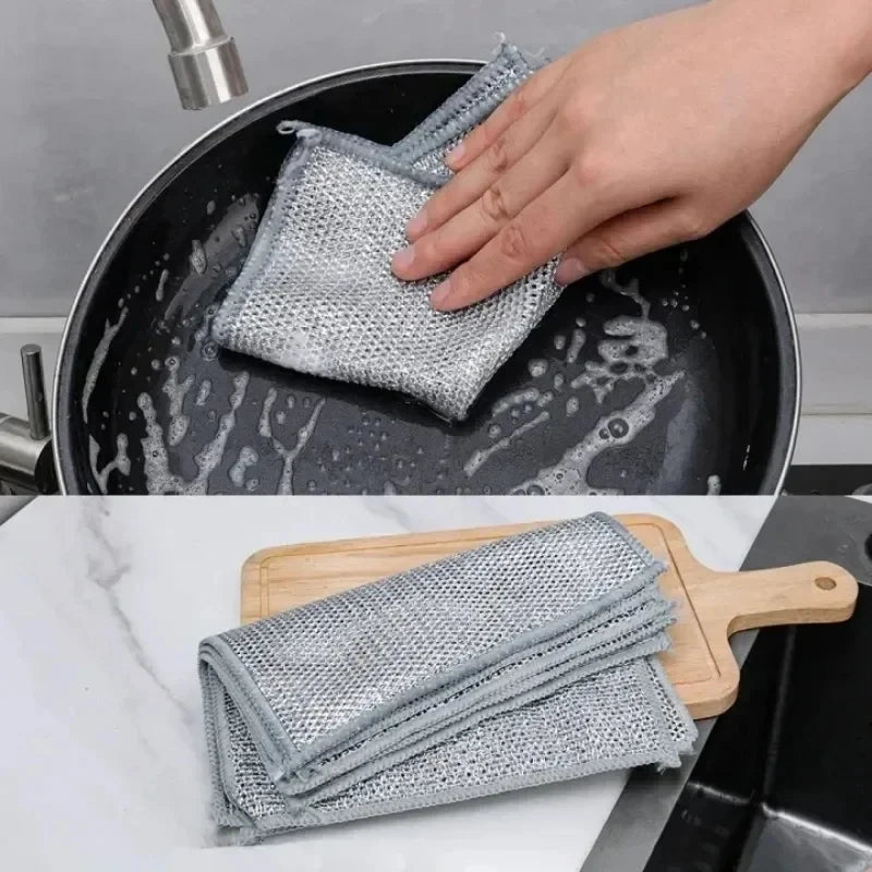 Eine Hand legt ein wiederverwendbares Drahtgeflecht-Tuch in eine schwarze Pfanne, mit einem Stapel ähnlicher Tücher auf einem