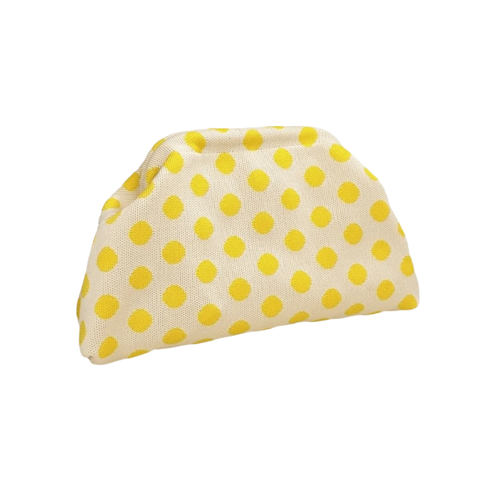 A light yellow clutch bag with a white background and scattered yellow polka dots.