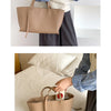 Une personne tient un sac fourre-tout en cuir PU beige contre un fond blanc.