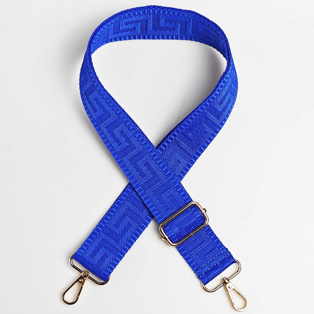 A royal blue adjustable crossbody bag strap featuring a maze pattern and gold-toned hardware.