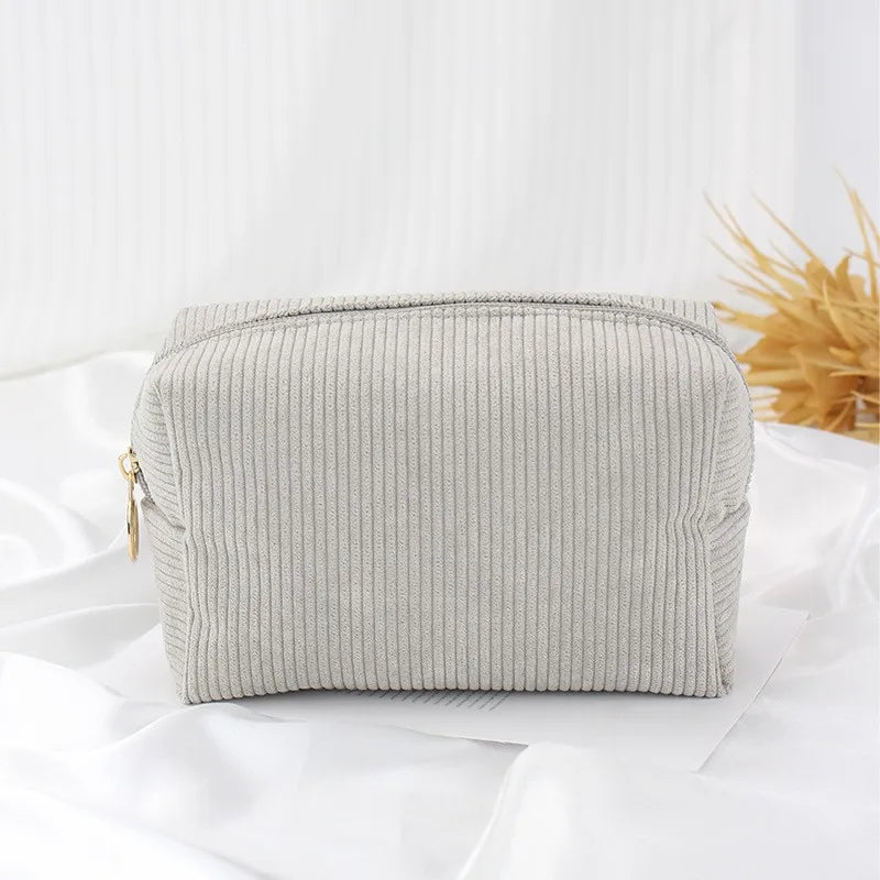 A light gray corduroy makeup organizer bag with an octagonal design lying on a white surface.