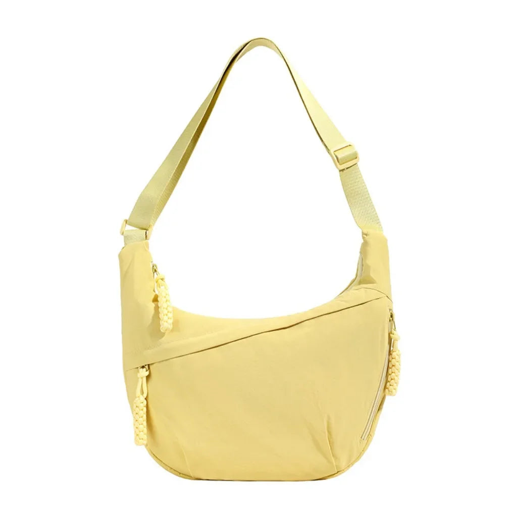 A light yellow canvas crossbody bag with a thin strap shown from the front.