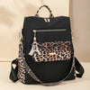 A black fashion backpack featuring a leopard print fabric panel and gold hardware.