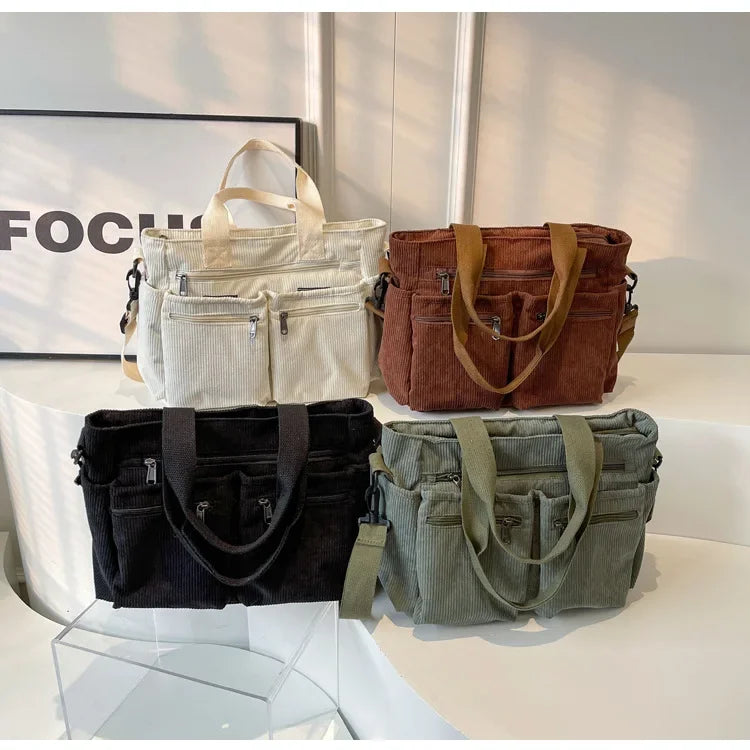A display of four textured corduroy tote bags in cream, brown, black, and olive green.