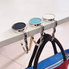 Metal desk hooks with silver rings are displayed on a white desk, ready for hanging bags and garments.