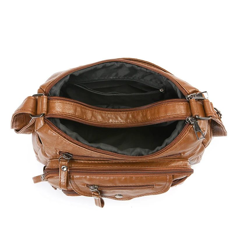 A brown leather tote bag with a flap closure and metal hardware, shown open.