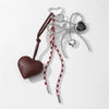 A brown heart-shaped key chain bag charm with a leather strap and silver chains.