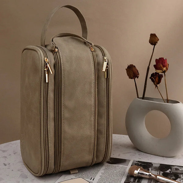 A beige waterproof PU leather travel cosmetic bag standing on a white surface.