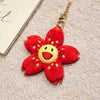 A bright red sunflower plush keychain with a yellow center and gold-colored chain.
