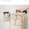 A beige portable luggage shoe organizer bag with multiple compartments is shown resting on a silver suitcase.