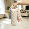 A hand is holding a quilted storage bag for hair dryer and personal items with various fabric patterns.