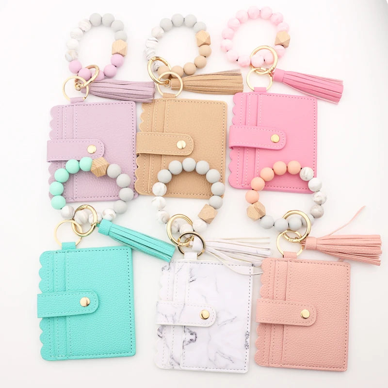 A collection of silicone bead bracelets and leather card holders in various shades of pink, beige, mint green, and white.