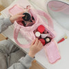 A hand is opening a pink multipocket travel toiletry bag revealing various makeup and skincare products.