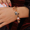 A hand wearing a Halloween pumpkin ghost charm bracelet with gold and black beads.