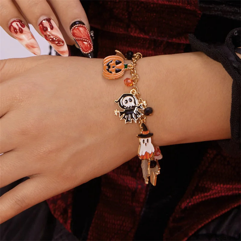 A hand wearing a Halloween pumpkin ghost charm bracelet with gold and black beads.