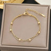 Gold stainless steel charm bracelet with a portrait pendant displayed in a box.