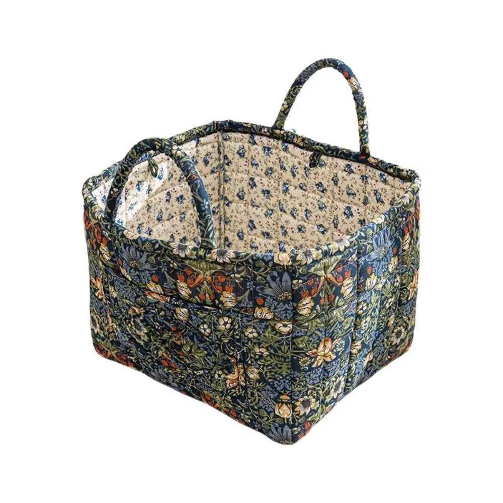A quilted fabric storage basket with carry handles featuring a floral pattern in blue, green, and brown tones.