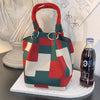 A red and green plaid knitted bucket handbag resting on a white circular mat.