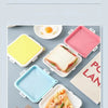 A collection of silicone reusable sandwich and lunch containers in various colors like yellow, pink, and blue, shown on a lig