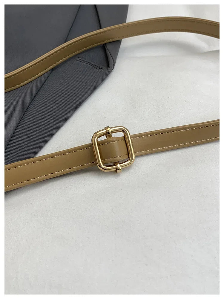 A close-up of a Michael Kors Classic Letter Square crossbody bag featuring tan leather strap and gold hardware.
