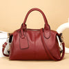 A maroon soft leather tote bag with a zipper and adjustable shoulder strap is shown against a light background.