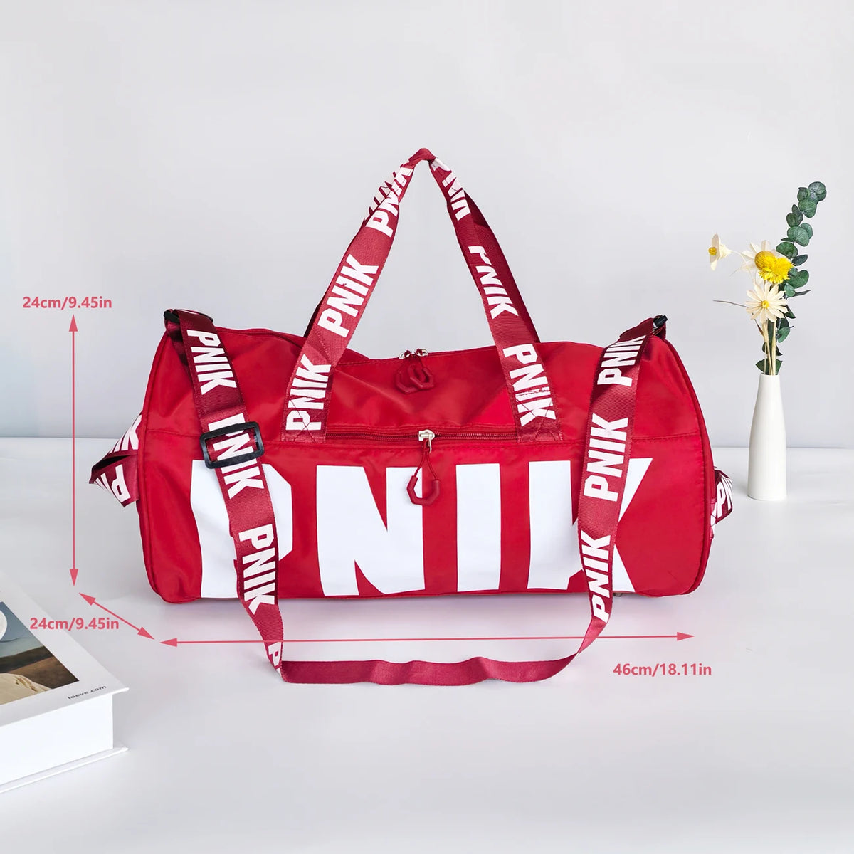 A red and white printed shoulder bag with pink fabric handles is shown on a white surface.