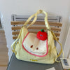 A yellow nylon messenger backpack shaped like a face with a red apple detail.