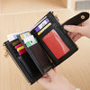 A black leather wallet with gold accents and various cards is held by a hand against a light wooden background.