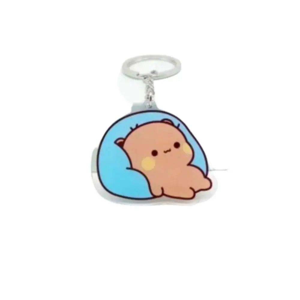 A cute cartoon character charm of a light brown, round creature set in a blue oval resin with a silver keyring.