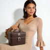 A woman models a brown double-layer makeup storage case with gold accents.