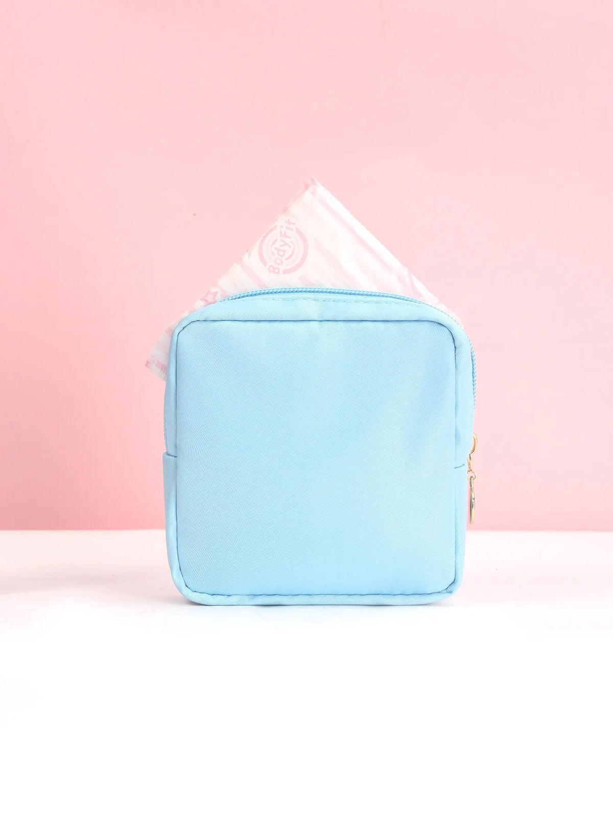 Helle blaue tragbare Tasche zum Aufbewahren von Damenbinden, auf rosa Hintergrund.