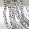 A close-up of strands of clear and iridescent faceted crystal glass beads in a wheel shape for jewelry making