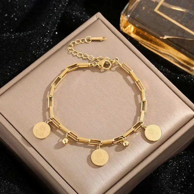 Gold stainless steel charm bracelet with a portrait pendant displayed in a box.