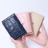 A hand holds a mini crocodile pattern leather card holder in navy blue and blush pink.