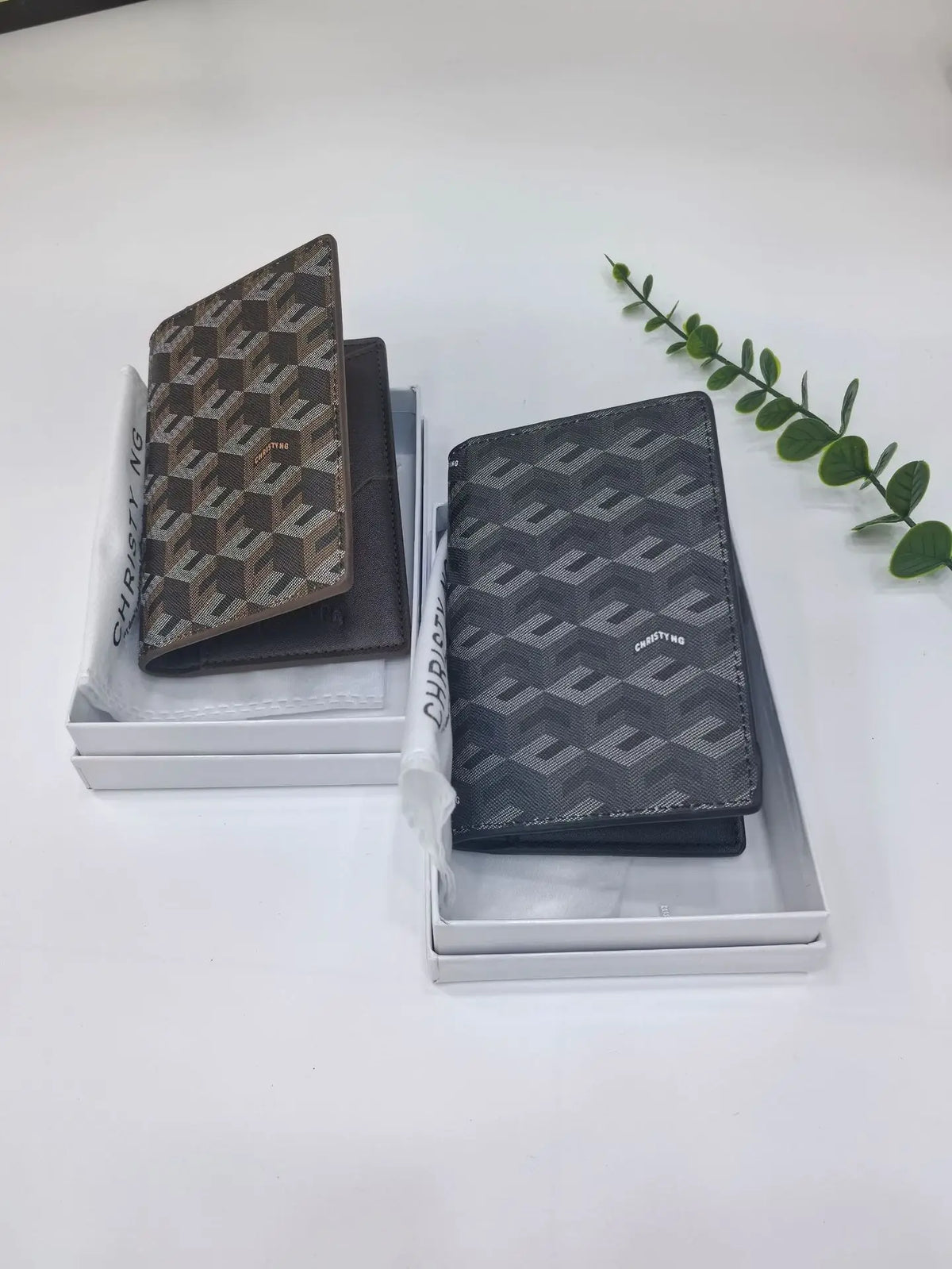 A dark gray geometric print passport wallet displayed in its packaging on a white surface.
