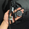 A hand holds a black D-shape nylon fitness keychain with a circular fitness charm.