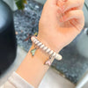 A hand is wearing a beige and white striped replacement elastic watch strap for a Huawei band.
