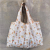 A white reusable shopping bag with a floral pattern is hanging on a metal hook.