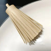 A bundle of light beige leather tassel fringe craft supplies laid diagonally on a white plate.