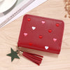 A red compact PU leather wallet with a zipper closure decorated with small pink and white heart embellishments and attached t