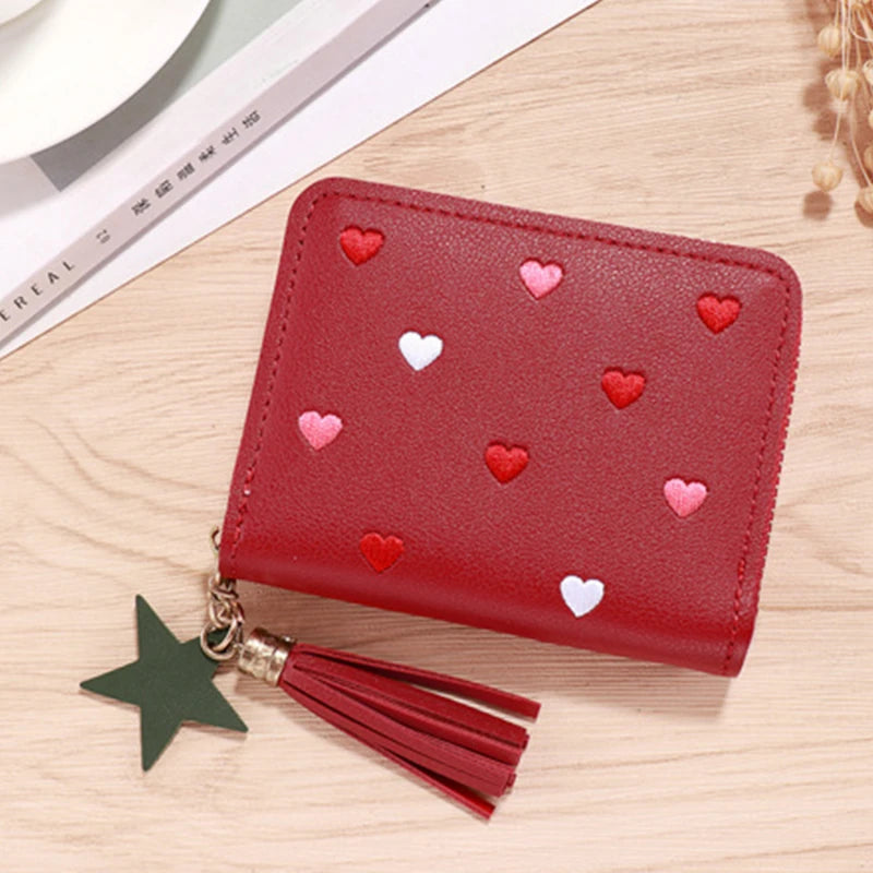 A red compact PU leather wallet with a zipper closure decorated with small pink and white heart embellishments and attached t