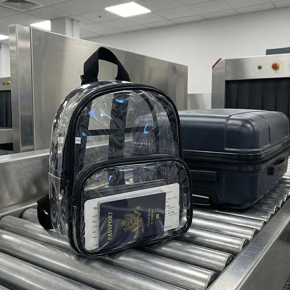 A transparent PVC daypack containing a passport is placed on a metal conveyor belt.