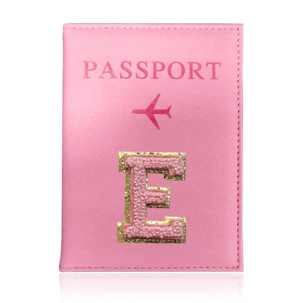 A pink leather passport holder with the embossed letter E and a small airplane symbol.