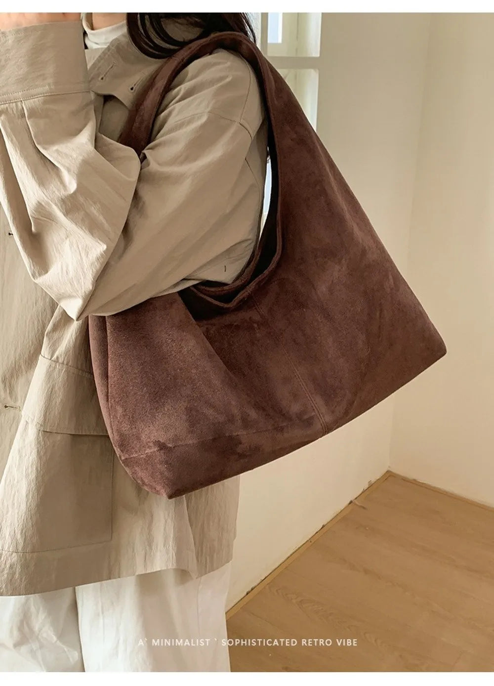 A close-up of a person wearing a beige shirt and carrying a brown suede shoulder tote bag.
