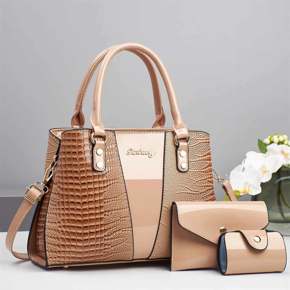 Bolso y cartera de cuero grabado de cocodrilo marrón exhibidos sobre una superficie blanca.