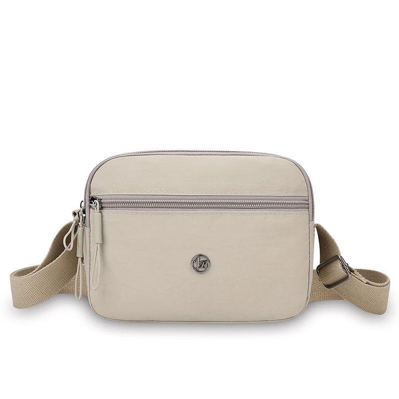 A beige nylon crossbody bag with a zipper closure and adjustable strap.