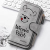 A gray zippered pouch featuring a cartoon bear face with a red nose, resting on a white background next to a laptop keyboard.