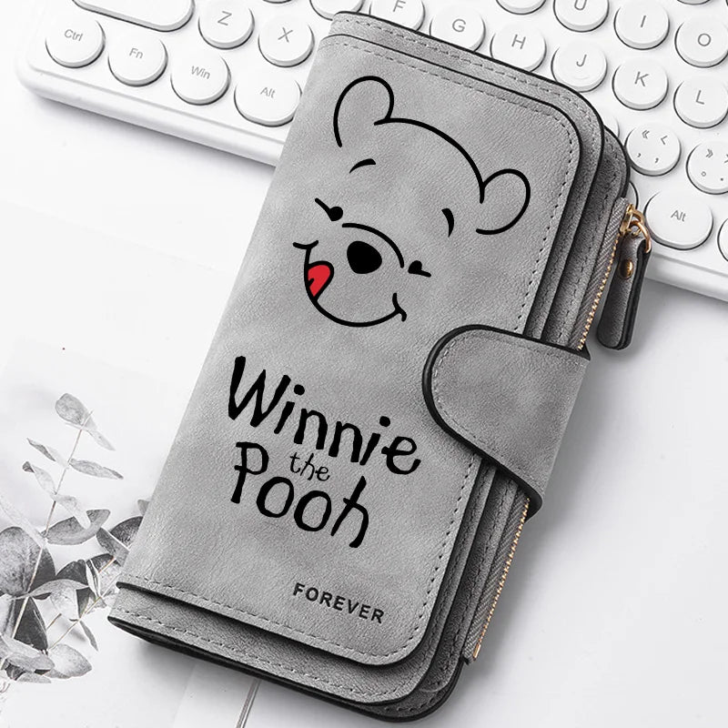 A gray zippered pouch featuring a cartoon bear face with a red nose, resting on a white background next to a laptop keyboard.