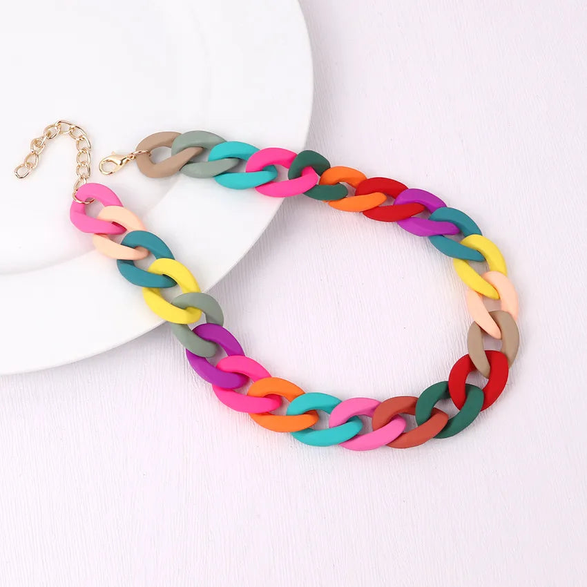 A colorful acrylic statement choker necklace featuring multiple braided strands in shades of pink, orange, green, and brown.